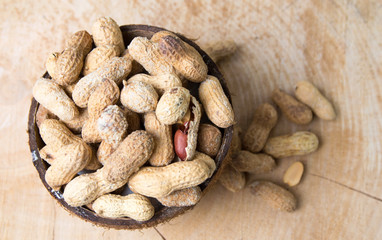 Peanuts with natural shells in coconut bowl