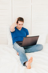 Man working at a laptop sitting on the bed