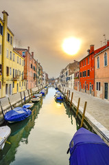 Fototapeta na wymiar one of the many canals of Venice, deserted in the sunset with typical colorful houses architecture