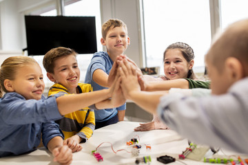 happy children making high five at robotics school