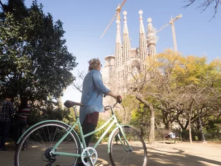 Tuinposter Young woman tourist with bicycle in front of Sagrada Familia in Barcelona 5 © Daniel