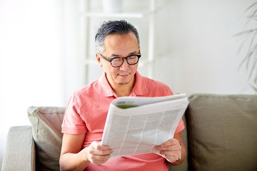 happy man in glasses reading newspaper at home