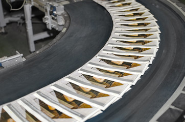 Working print machine with magazines on conveyor belt