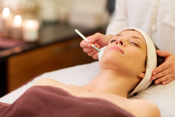 Obraz na płótnie Canvas beautician applying facial mask to woman at spa