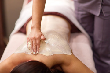 woman having back massage with cream at spa