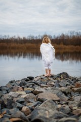 Angel boy on rocks near the river in spring outdoors