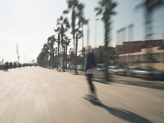 Young blonde modern woman riding her skateboard at the boardwalk of Barcelona