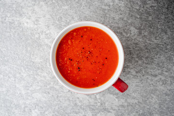 Tomato soup in ceramic bowl on stone background.