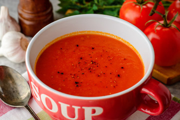 Tomato soup in ceramic bowl on stone background.