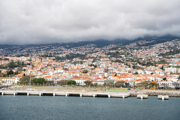 Fototapeta premium beautiful coastal houses with red roofs near mountain and boats