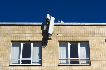 Fototapeta na wymiar antenna mobile operator on the wall on blue sky