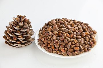 small pine nuts on plate in the shell on white background