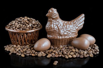 Beans coffee and chocolate in the form of chicken and eggs on a black background