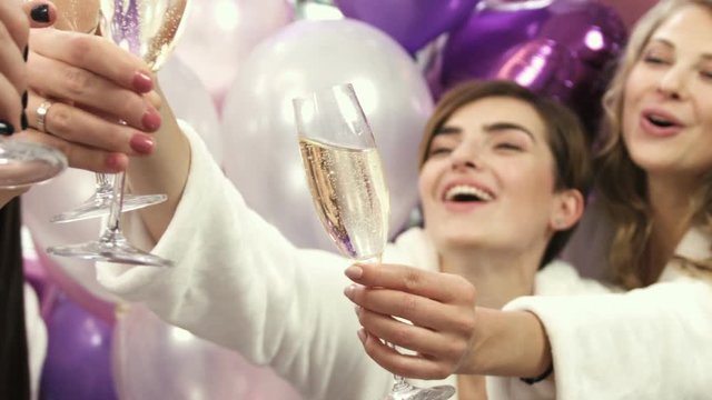 Close up of beautiful girls in white robes drinking champagne at the opening party. Women celebrating at the beauty salon. Champagne glasses