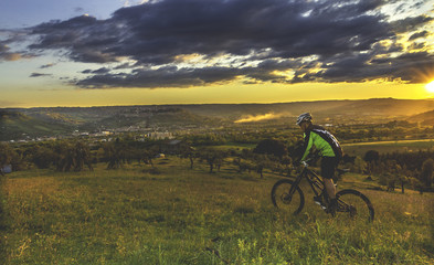 Fototapeta na wymiar Cyclist Riding the Bike on the beautiful landscape in a stormy sunset. Sport Concept