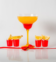 Colorful drink in a margarita glass, red and orange combination, four drinks in a shotglass,red bow