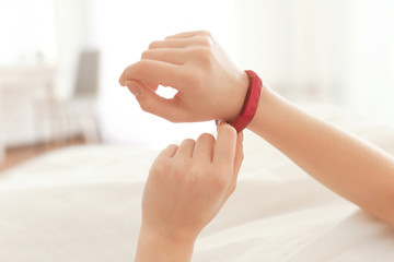 Hands of young woman with sleep tracker lying in bed at home
