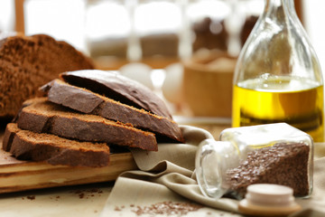 Cut bread, napkin and jar with seeds on kitchen table