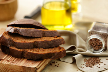 Cut bread, napkin and jar with seeds on kitchen table
