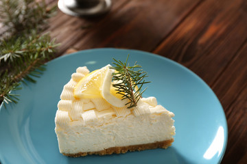 Piece of delicious cheesecake with lemon on blue plate
