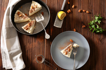 Pieces of delicious cheesecake with almonds on wooden table