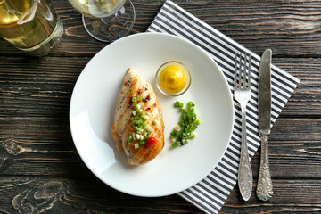Plate with delicious chicken breast on napkin