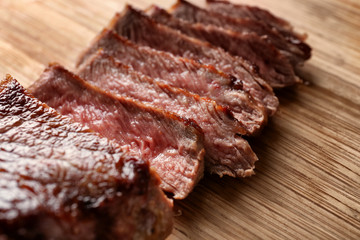 Sliced tasty steak on wooden board