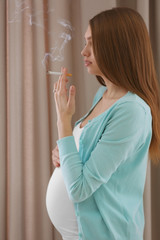 Pregnant woman smoking cigarette on curtains background