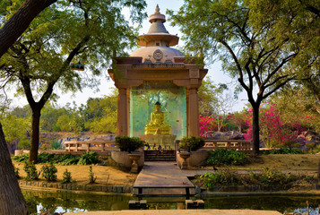 A sitting Buddha in Jayanti Park overlooking a scenic pond with birds catching the reflection of the sun.