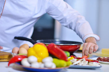 mature chef preparing a meal with various vegetables and meat