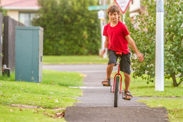 outdoor portrait of young boy riding a unicycle on natural background
