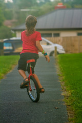 outdoor portrait of young boy riding a unicycle on natural background