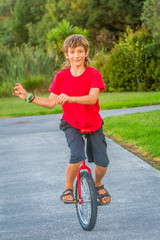 outdoor portrait of young boy riding a unicycle on natural background © Alena Yakusheva
