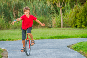 outdoor portrait of young boy riding a unicycle on natural background © Alena Yakusheva