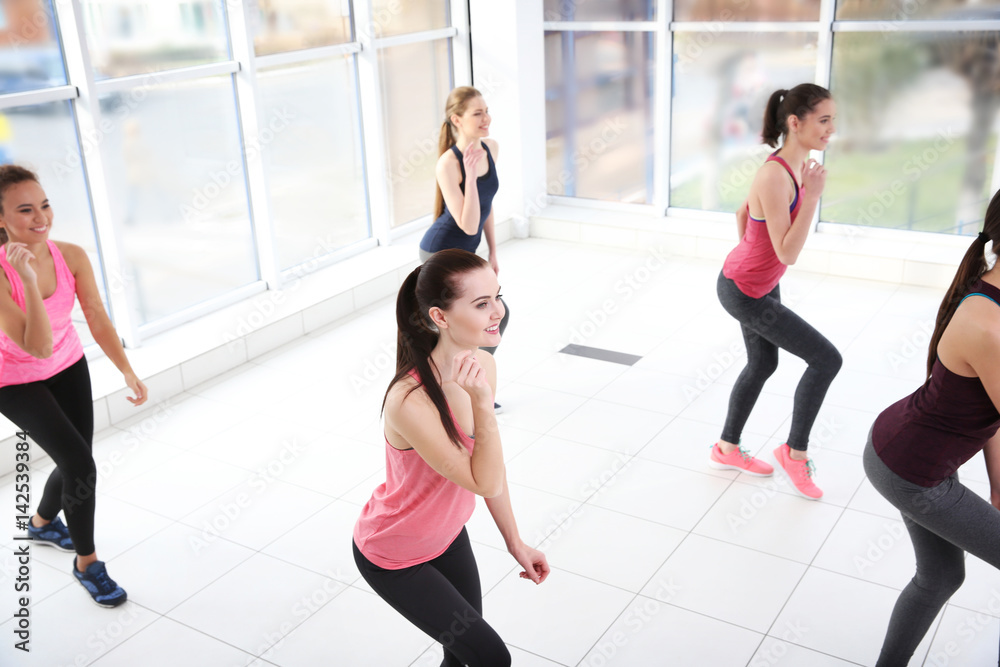 Poster Young sporty women training in dance hall