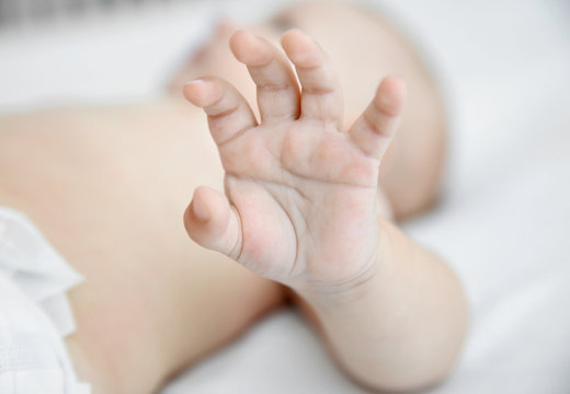Hand of little baby in crib, closeup