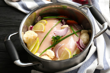 Raw chicken breasts with lemon and vegetables in saucepan