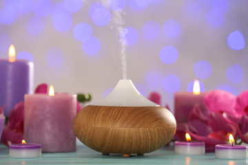 Aroma oil diffuser and candles on blurred background