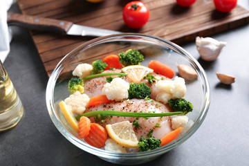 Marinating chicken with vegetables in glass bowl