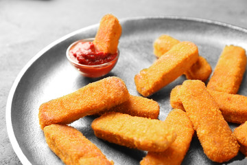 Metal plate with cheese sticks and ketchup sauce on gray background