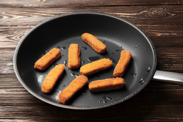 Pan with cheese sticks on wooden background