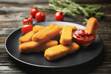 Plate with cheese sticks and ketchup sauce on wooden background