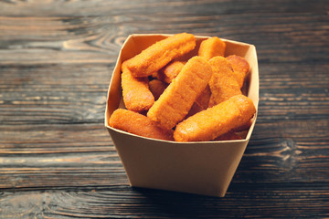 Paper box with cheese sticks on wooden background