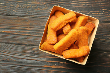 Paper box with cheese sticks on wooden background