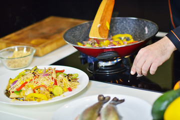 mature chef preparing a meal with various vegetables and meat