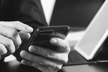 close up of businessman hand working with smart phone and laptop and digital tablet computer in modern office