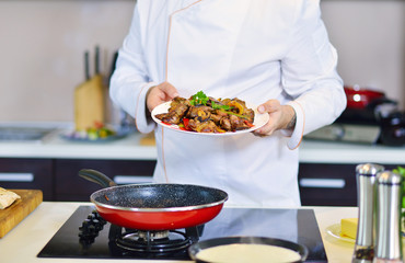 Cook holding plate with food in welcoming gesture