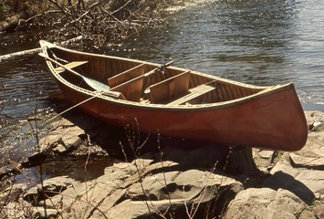 Vintage wooden fishing canoe on the shore of a river 