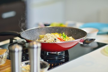 Vegetable ragout in pan, on wooden table on bright background