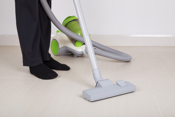 woman legs with vacuum cleaner cleaning floor